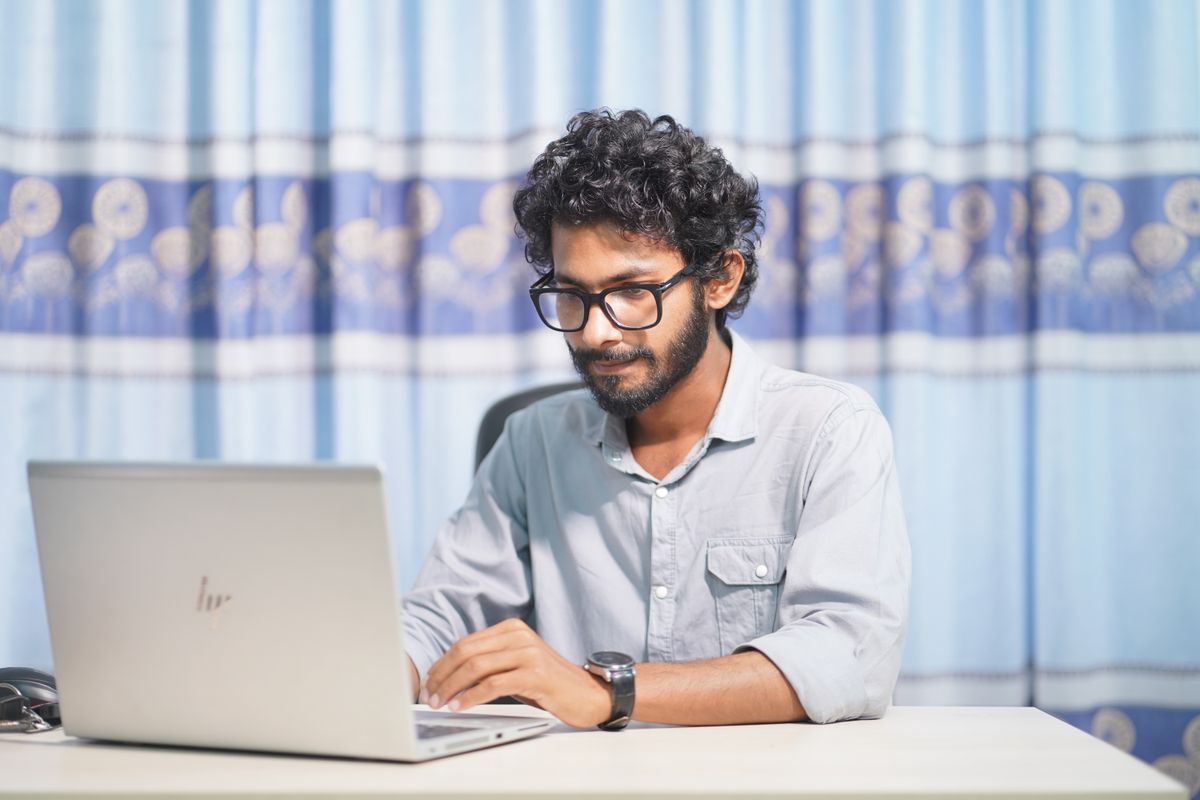 Jeune dirigeant concentré travaillant seul sur son ordinateur portable dans un bureau lumineux