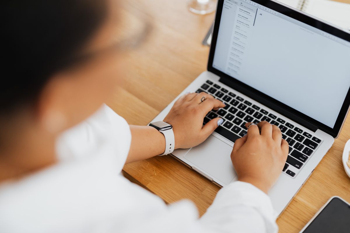Personne tapant sur un ordinateur portable affichant une messagerie professionnelle avec plusieurs emails