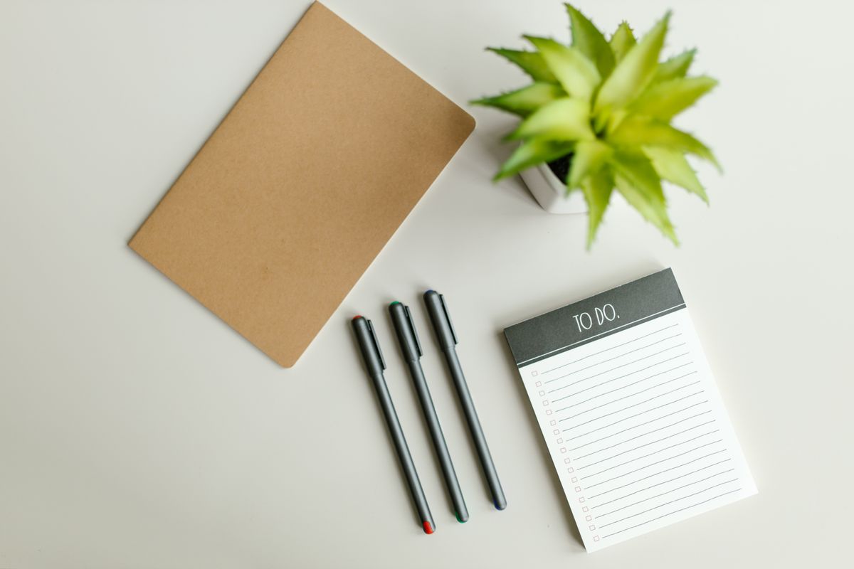 Liste de tâches, carnet et stylo posés sur un bureau clair pour organiser son travail