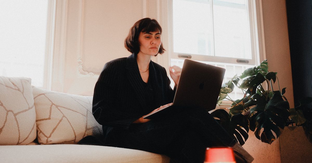 Femme en télétravail installée sur un canapé avec son ordinateur portable