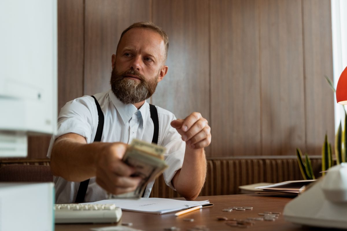 Homme d'affaires dans un bureau d'entreprise manipulant une liasse de billets sur son bureau