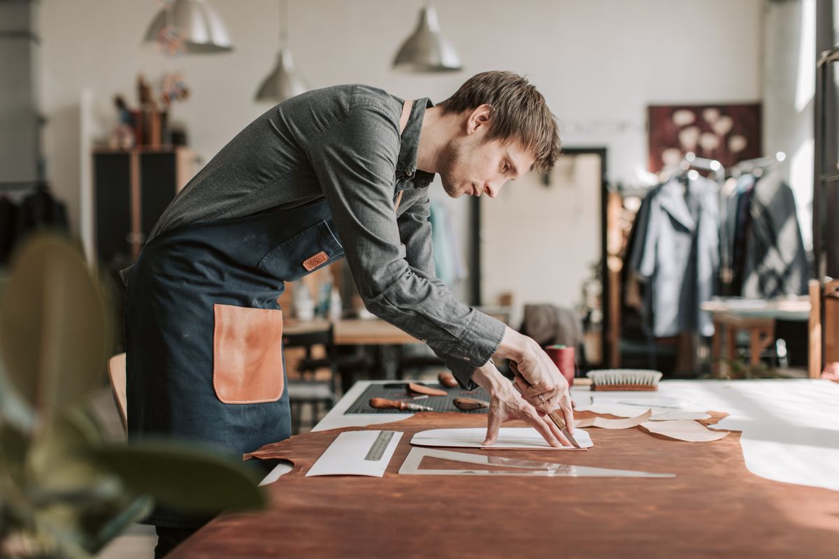 Mains d'un artisan travaillant le cuir dans un atelier de maroquinerie